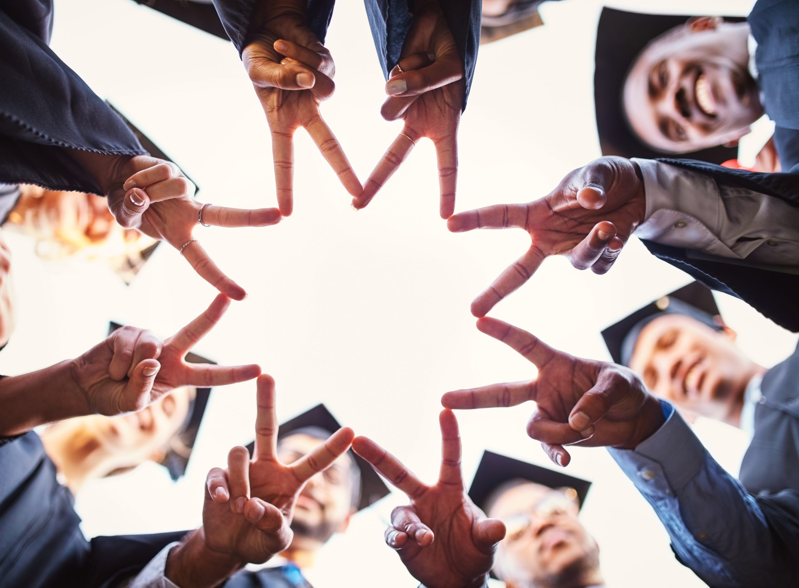 Graduates in caps stand in a circle, their hands pointing inward to form a star shape against the sky—a perfect moment for your Sample Post, capturing the essence of unity and achievement.