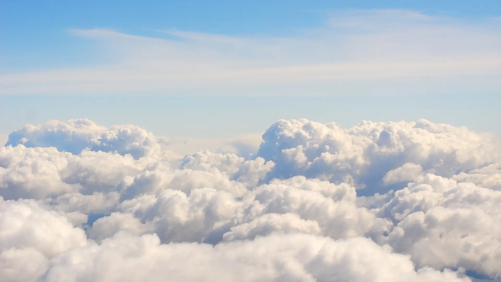 Fluffy white clouds fill the sky under a clear blue backdrop.