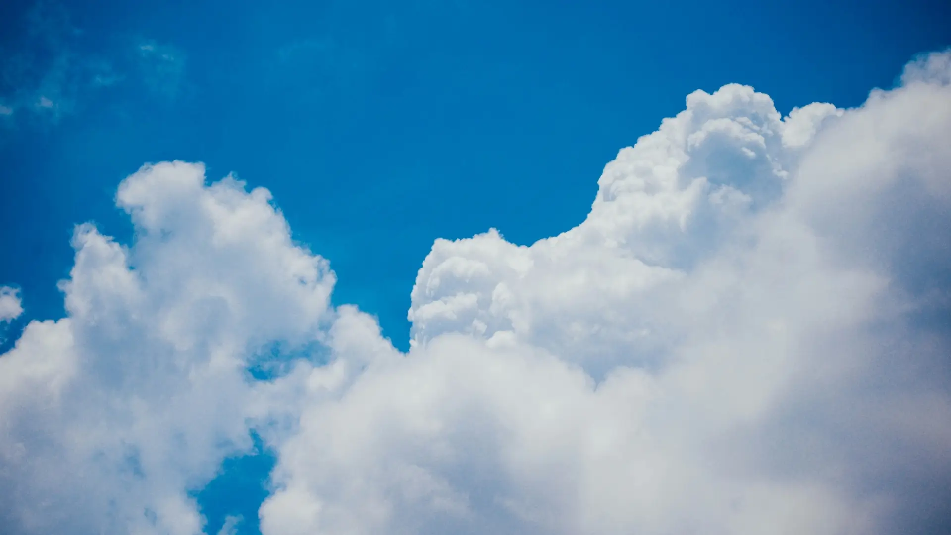 Fluffy white clouds against a bright blue sky.