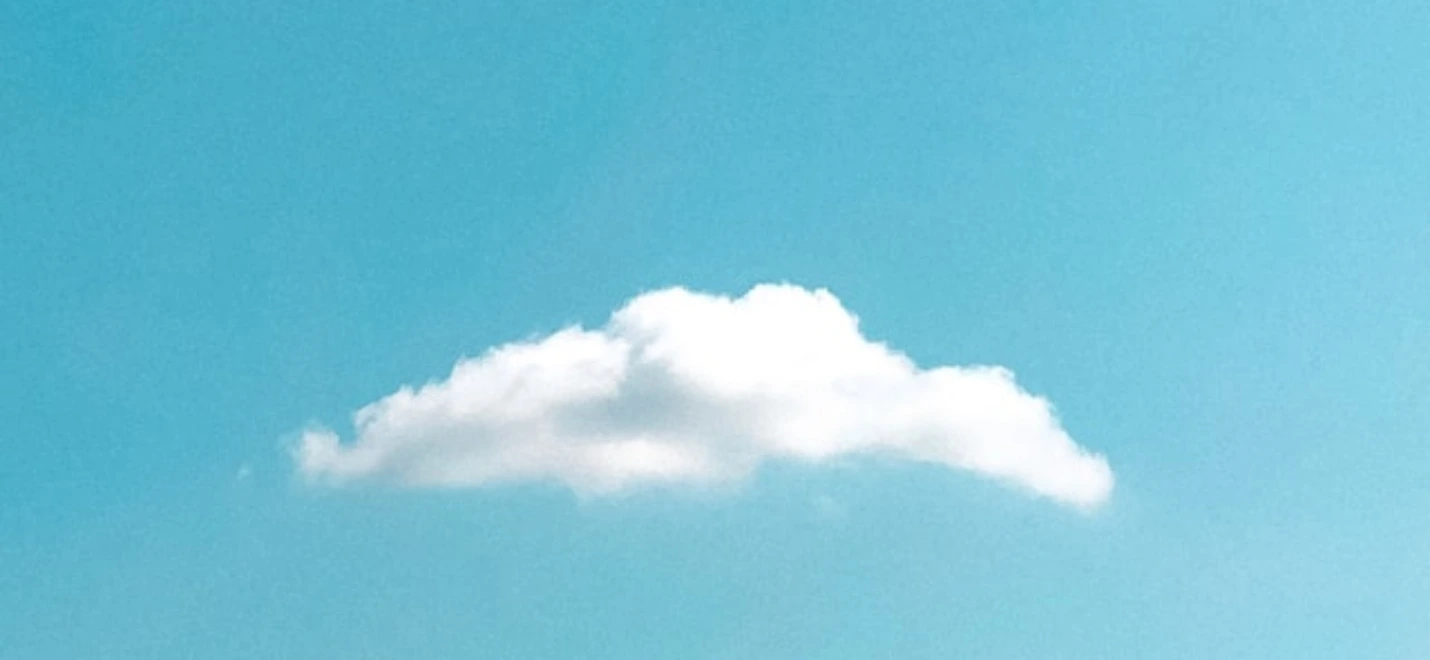 A single, fluffy white cloud floats against a clear blue sky.